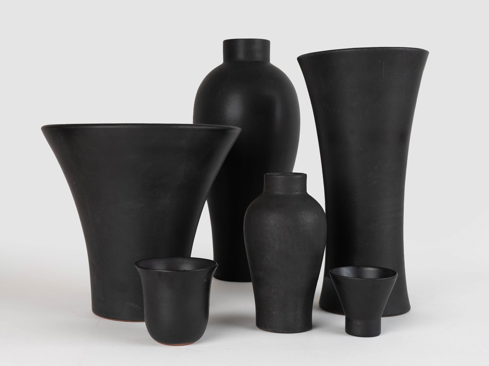 The Iteru stoneware family together in black glaze — vases, a beaker and a goblet cup