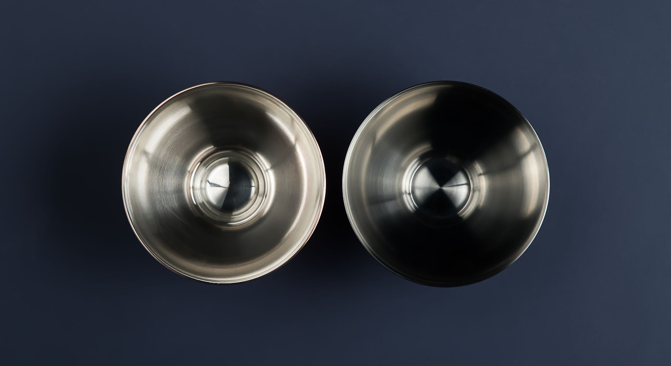 Two bowls seen from above on deep blue, one mirror-polished and one blackened