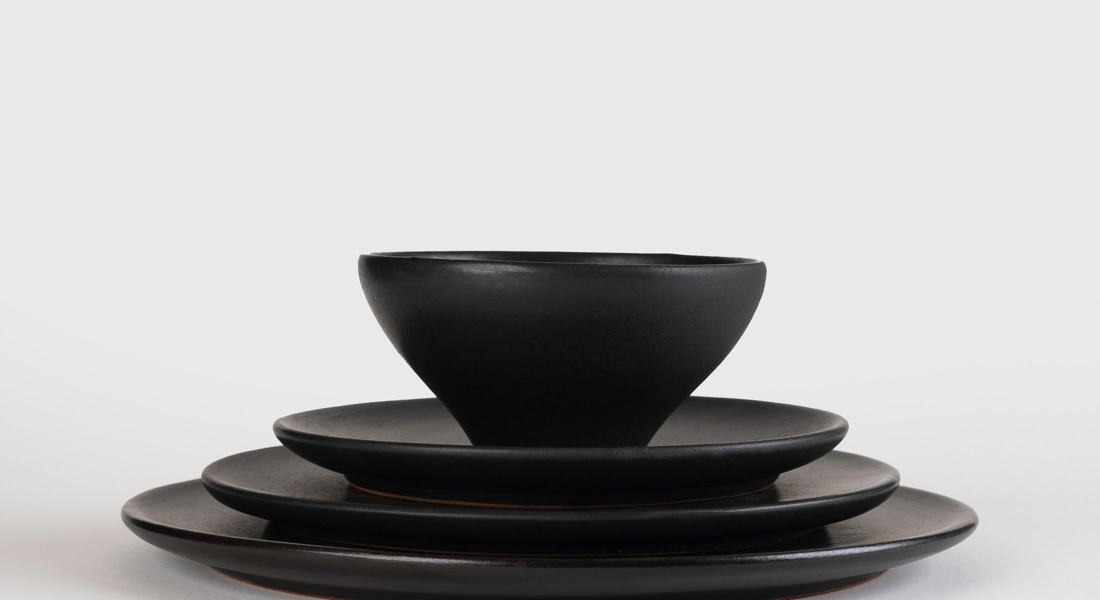 Iteru stoneware in black glaze — a bowl resting on three stacked plates