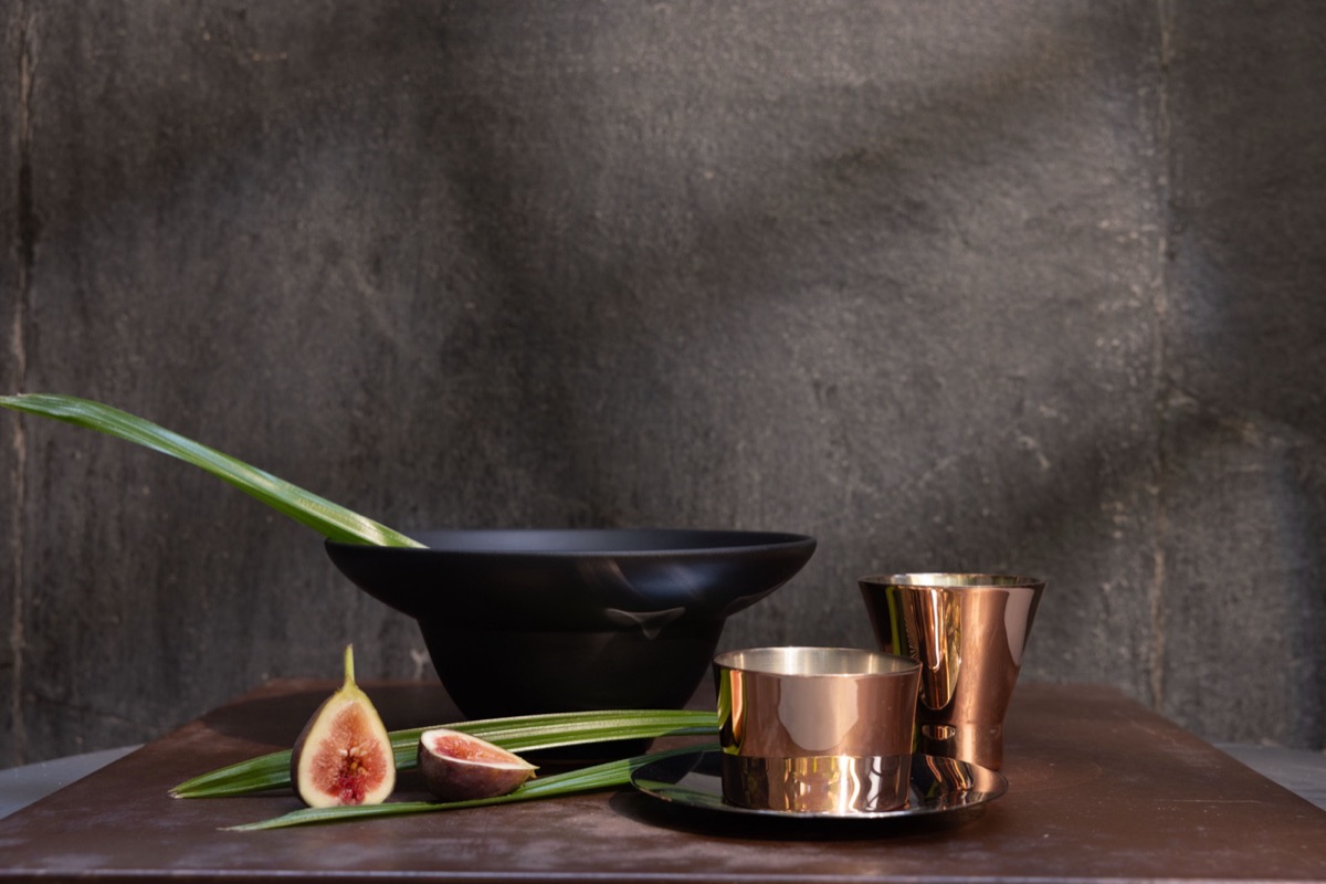 A dark bowl and copper cups with figs